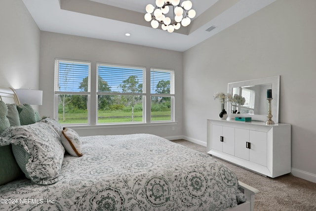 bedroom featuring a tray ceiling, multiple windows, light carpet, and a chandelier