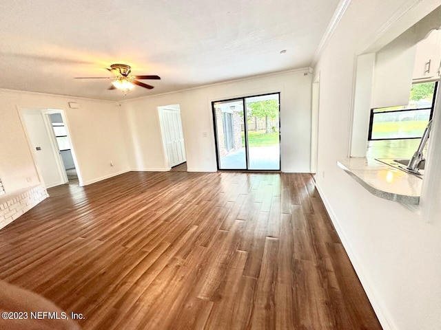 unfurnished living room with dark wood-type flooring, ornamental molding, and ceiling fan