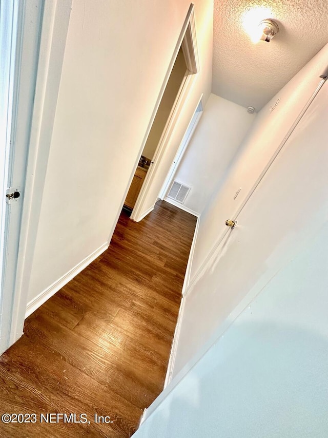 hallway with dark hardwood / wood-style floors and a textured ceiling