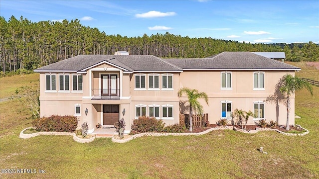 view of front facade with a balcony, a front lawn, and a patio area