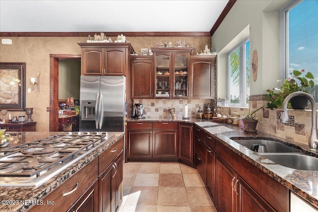 kitchen with sink, backsplash, stainless steel appliances, dark stone countertops, and crown molding