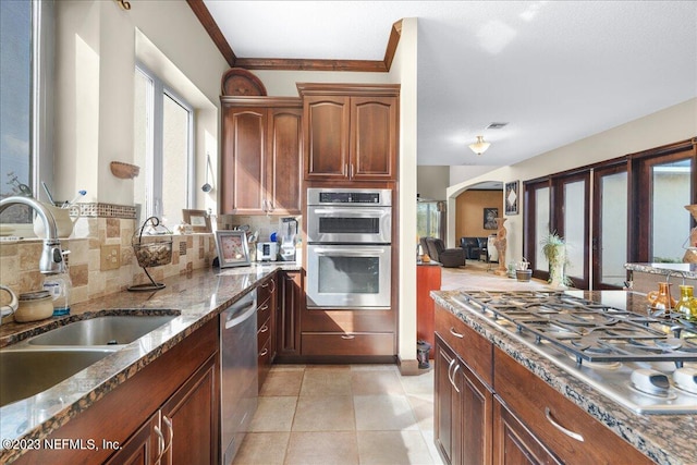 kitchen featuring light tile patterned floors, ornamental molding, sink, tasteful backsplash, and appliances with stainless steel finishes