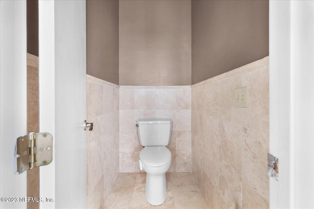 bathroom with tile walls and toilet