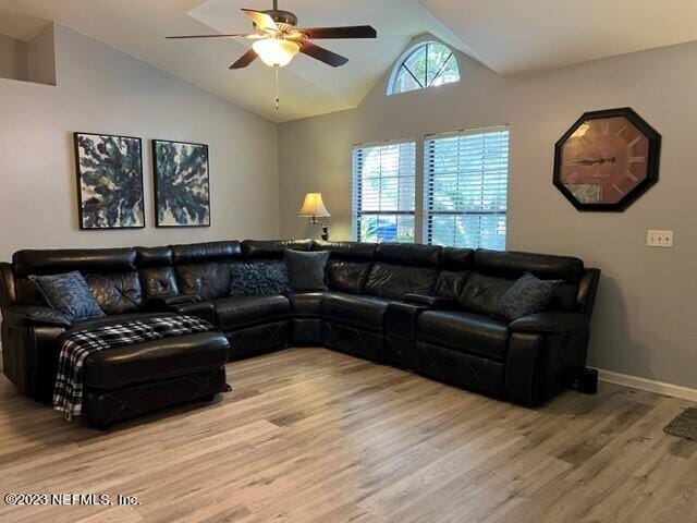 living room featuring hardwood / wood-style flooring, ceiling fan, and vaulted ceiling