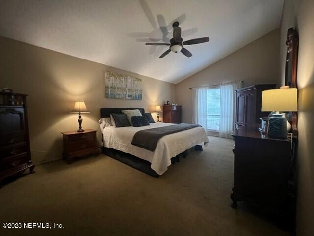 carpeted bedroom featuring ceiling fan and vaulted ceiling