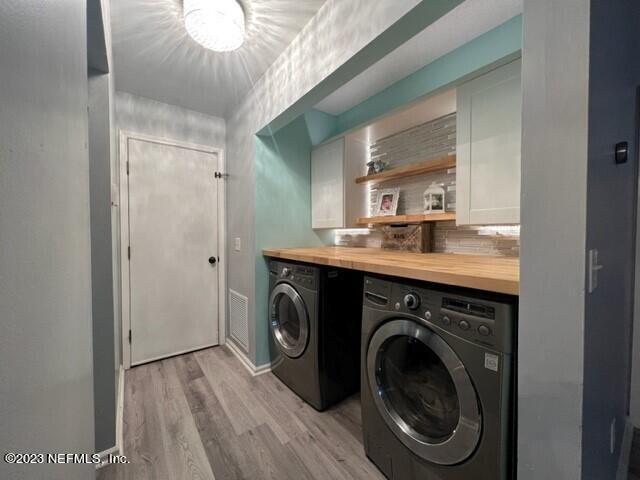 clothes washing area with separate washer and dryer and light wood-type flooring