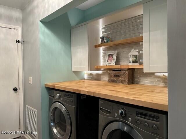 laundry room featuring cabinets, washing machine and clothes dryer, and bar area