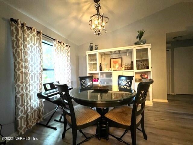 dining area featuring hardwood / wood-style flooring, lofted ceiling, and an inviting chandelier