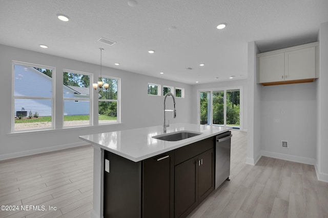 kitchen with dishwasher, sink, hanging light fixtures, light hardwood / wood-style flooring, and a kitchen island with sink