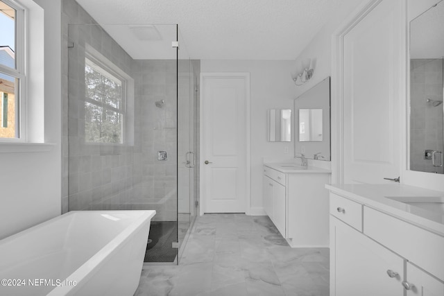 bathroom featuring plus walk in shower, a textured ceiling, and a wealth of natural light