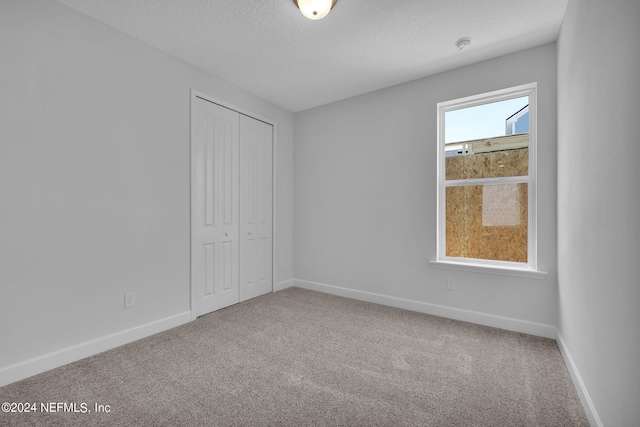 unfurnished bedroom featuring a textured ceiling, carpet floors, and a closet