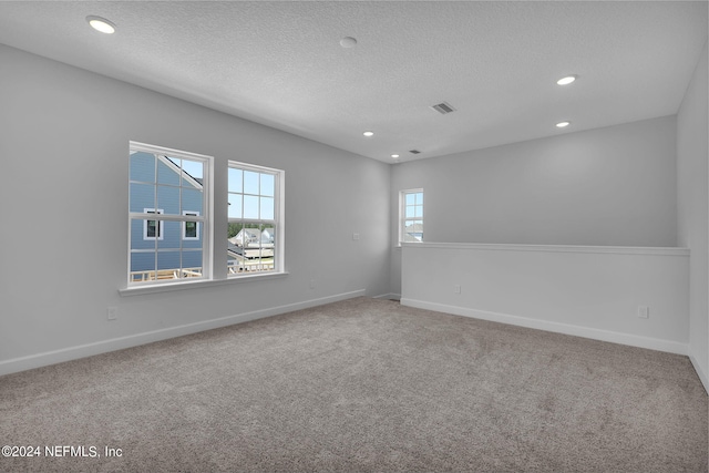 carpeted empty room featuring a textured ceiling