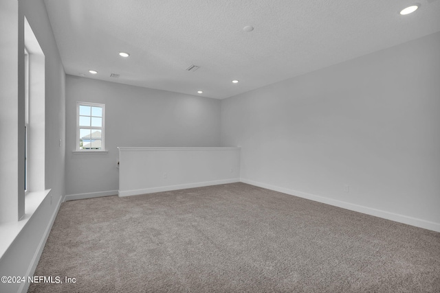 unfurnished room featuring light carpet and a textured ceiling