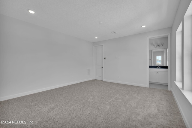 carpeted empty room featuring a textured ceiling and sink