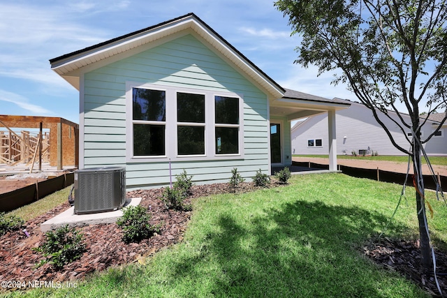 back of property featuring a yard and central AC