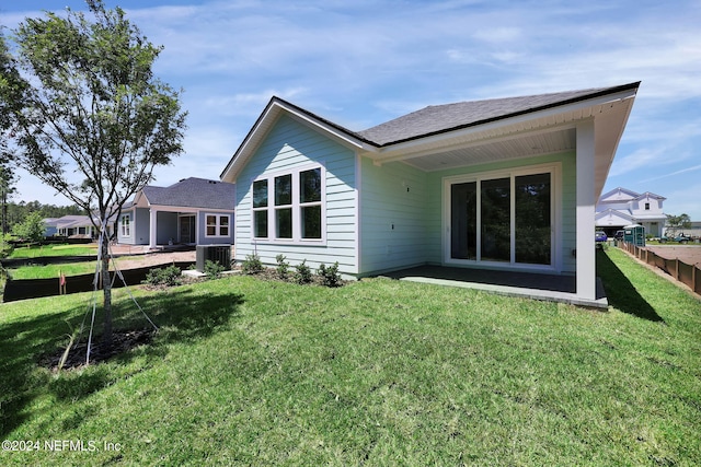 rear view of property featuring a yard and central AC unit