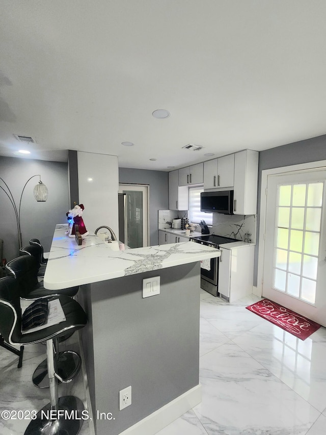 kitchen featuring a kitchen breakfast bar, a wealth of natural light, kitchen peninsula, and electric range