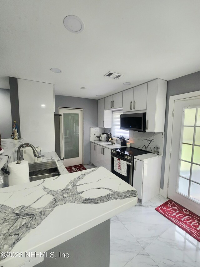 kitchen featuring backsplash, black / electric stove, sink, and kitchen peninsula