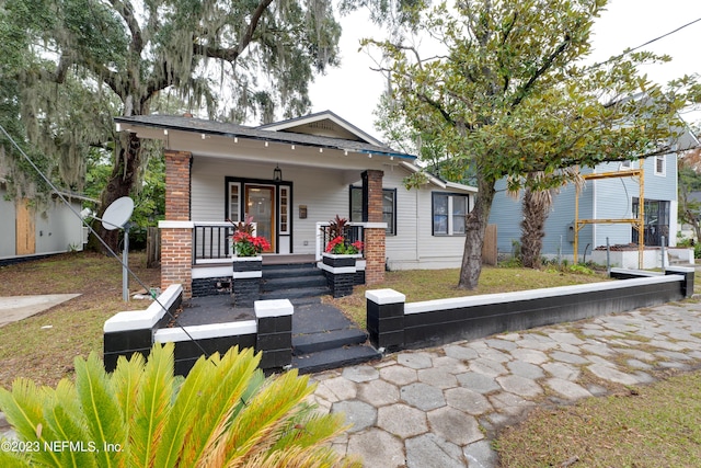 bungalow with covered porch and brick siding