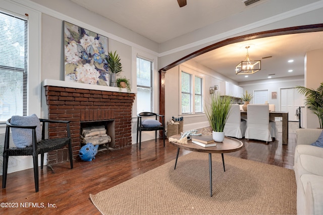 living area featuring a chandelier, a brick fireplace, wood finished floors, and recessed lighting