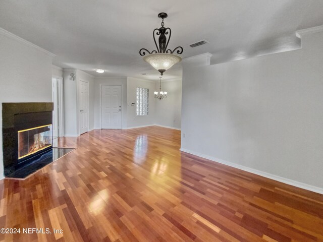 unfurnished living room with hardwood / wood-style flooring, ornamental molding, and an inviting chandelier