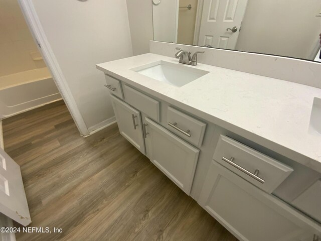 bathroom featuring shower / bathing tub combination, hardwood / wood-style floors, and vanity