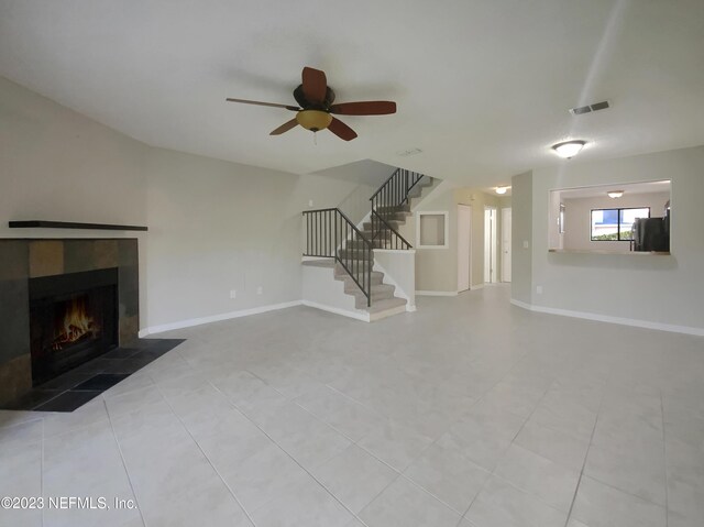 unfurnished living room featuring a fireplace, light tile patterned floors, and ceiling fan