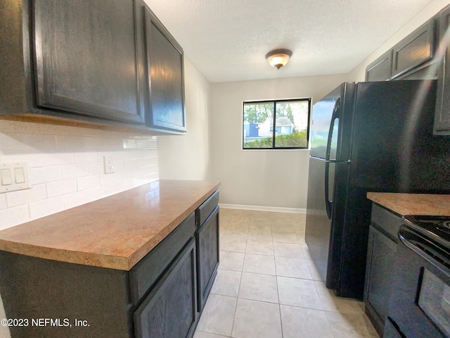 kitchen with stainless steel electric range oven, black refrigerator, light tile patterned floors, and a textured ceiling