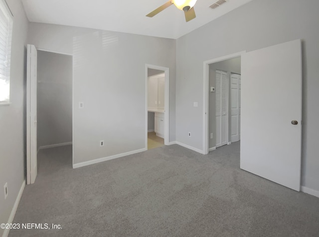 unfurnished bedroom with ensuite bath, ceiling fan, a walk in closet, light carpet, and a closet