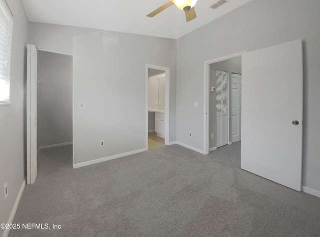 unfurnished bedroom with baseboards, ensuite bath, ceiling fan, a spacious closet, and carpet floors