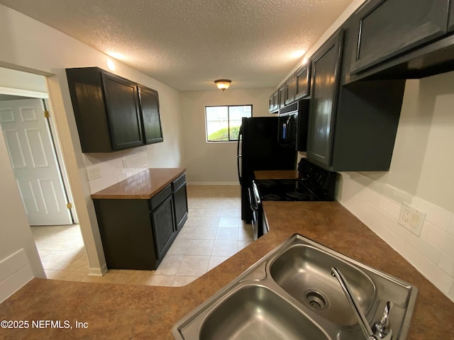 kitchen with light tile patterned floors, a textured ceiling, a sink, black appliances, and dark countertops