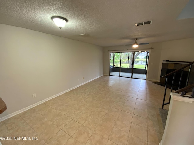 unfurnished living room with baseboards, visible vents, a ceiling fan, stairs, and a textured ceiling