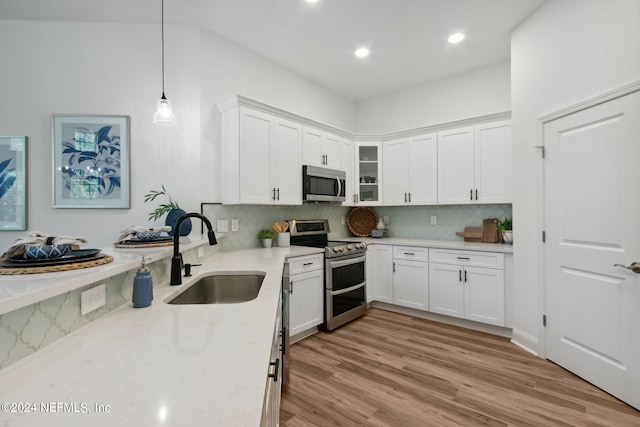 kitchen featuring white cabinets, stainless steel appliances, hanging light fixtures, and sink