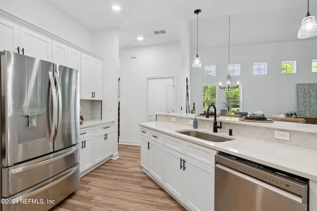 kitchen featuring stainless steel appliances, sink, pendant lighting, light hardwood / wood-style flooring, and white cabinets