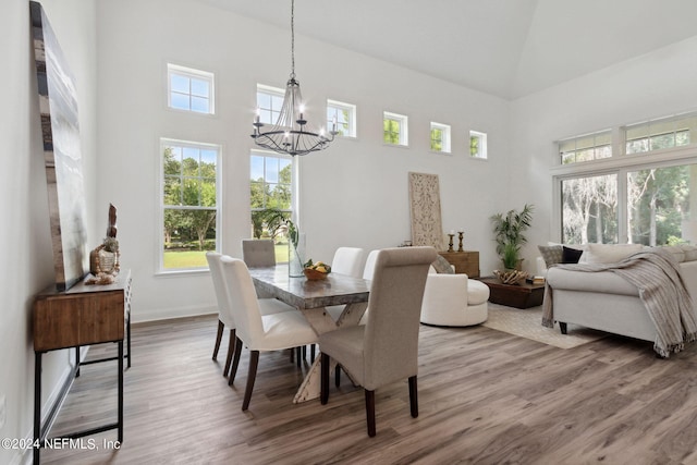 dining room with hardwood / wood-style flooring, a notable chandelier, and a high ceiling