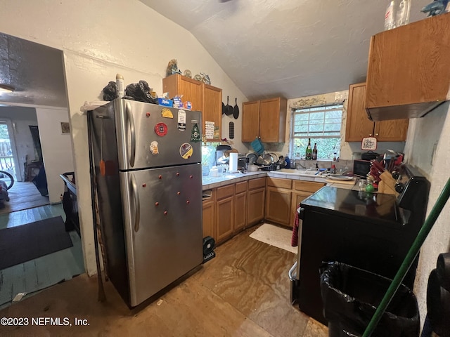 kitchen with black range with electric stovetop, lofted ceiling, and stainless steel refrigerator