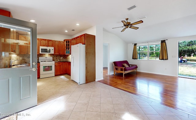 kitchen featuring tasteful backsplash, white appliances, vaulted ceiling, ceiling fan, and sink