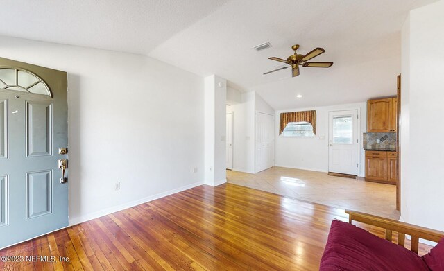 unfurnished living room with ceiling fan, light hardwood / wood-style floors, and vaulted ceiling