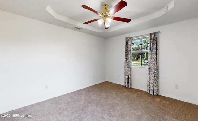 carpeted empty room with a tray ceiling and ceiling fan