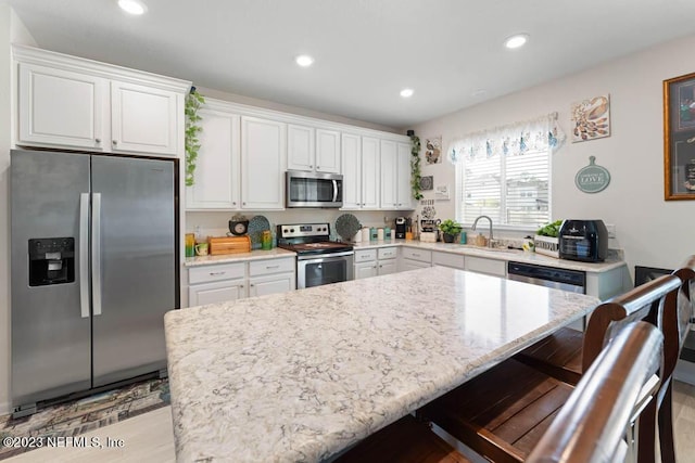 kitchen featuring sink, a breakfast bar area, white cabinets, a center island, and stainless steel appliances