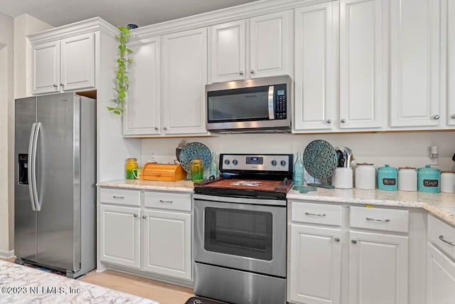 kitchen featuring light stone counters, appliances with stainless steel finishes, and white cabinets