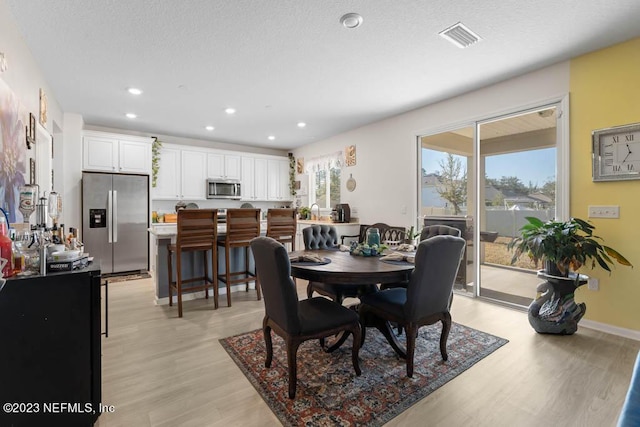 dining area featuring light hardwood / wood-style floors and a textured ceiling