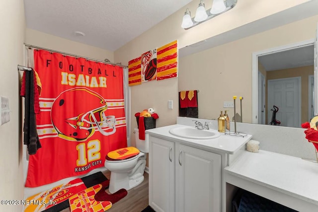 bathroom with wood-type flooring, vanity, walk in shower, toilet, and a textured ceiling