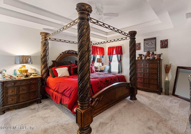 carpeted bedroom featuring a tray ceiling and ceiling fan