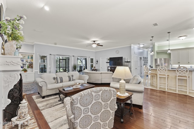 living room featuring ceiling fan, ornamental molding, a premium fireplace, and hardwood / wood-style floors