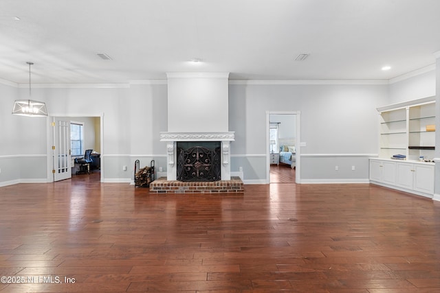 unfurnished living room with an inviting chandelier, ornamental molding, dark hardwood / wood-style floors, and a brick fireplace