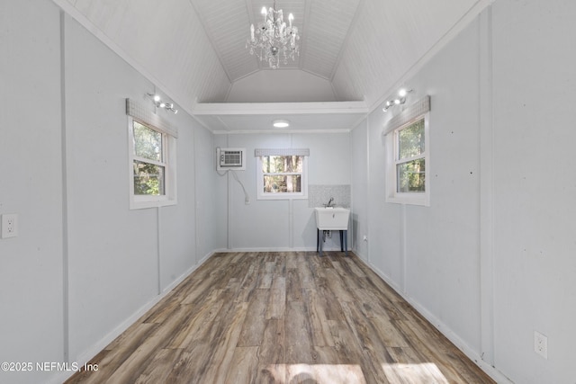 laundry room featuring an inviting chandelier, wood-type flooring, and an AC wall unit