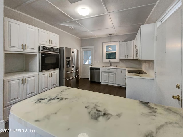 kitchen with black appliances, sink, white cabinetry, and hanging light fixtures