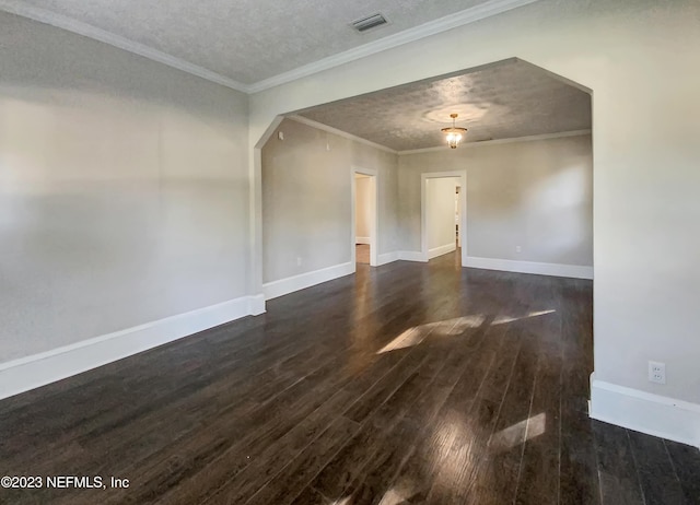 empty room with a textured ceiling, crown molding, and dark wood-type flooring