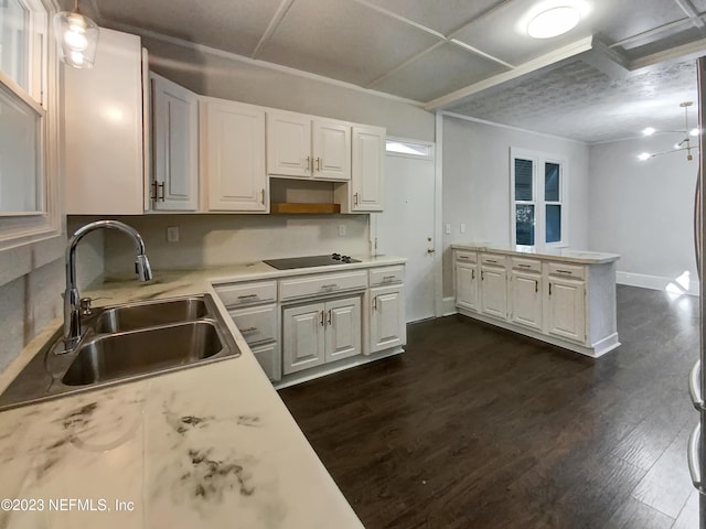 kitchen with dark wood-type flooring, black electric stovetop, sink, white cabinetry, and kitchen peninsula